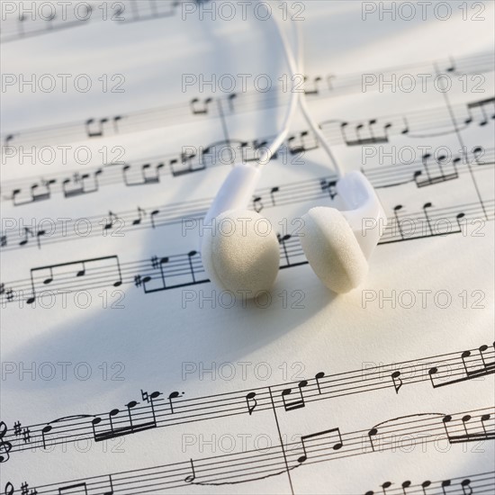 Close up of ear buds on sheet music.