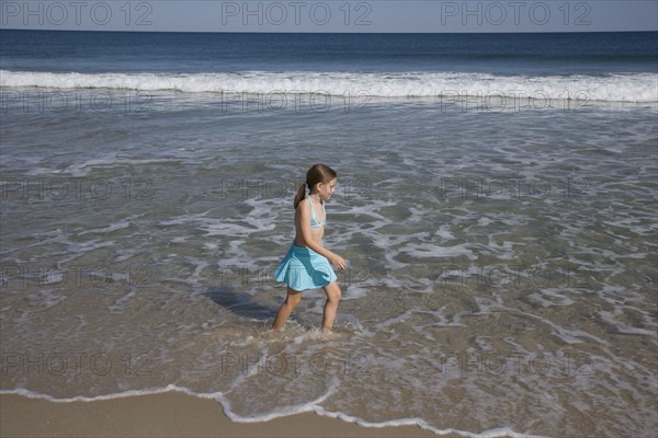 Girl walking in ocean surf.