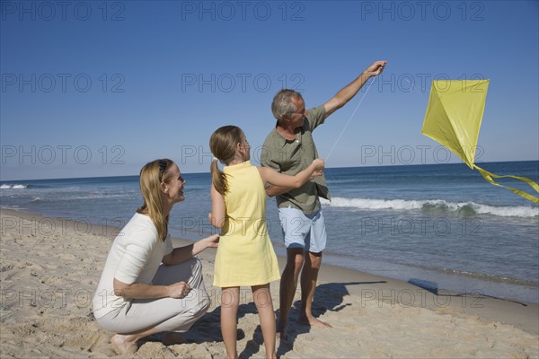 Family flying kite at beach.