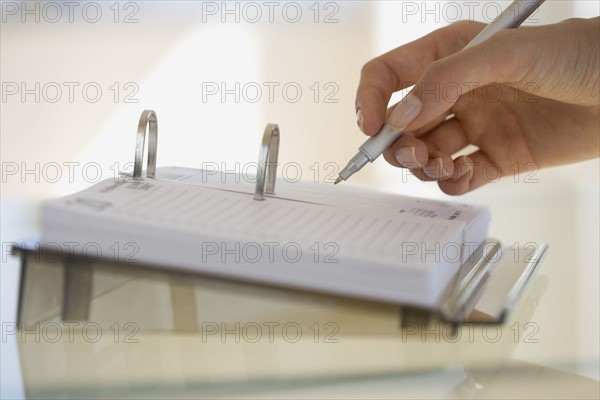 Woman writing on desk calendar.