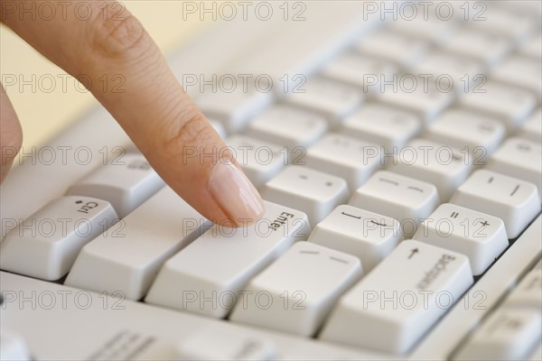 Woman pressing Enter key on computer keyboard.