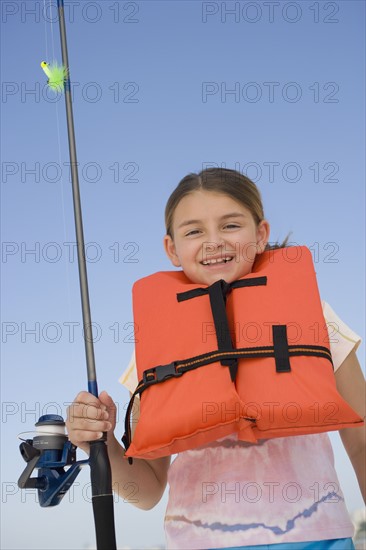 Girl in life jacket holding fishing pole.