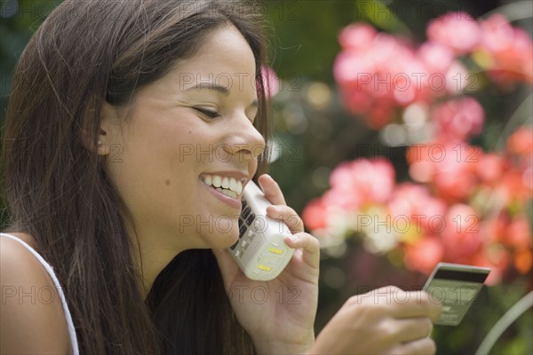 Woman on phone holding credit card. Date : 2006