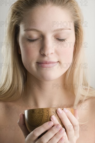 Woman meditating and holding wooden cup. Date : 2006