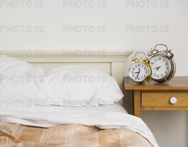 Unmade bed with alarm clocks. Date : 2006