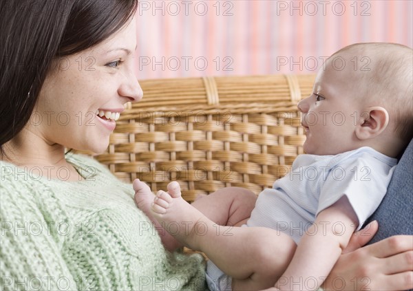 Mother smiling at baby on her lap. Date : 2006