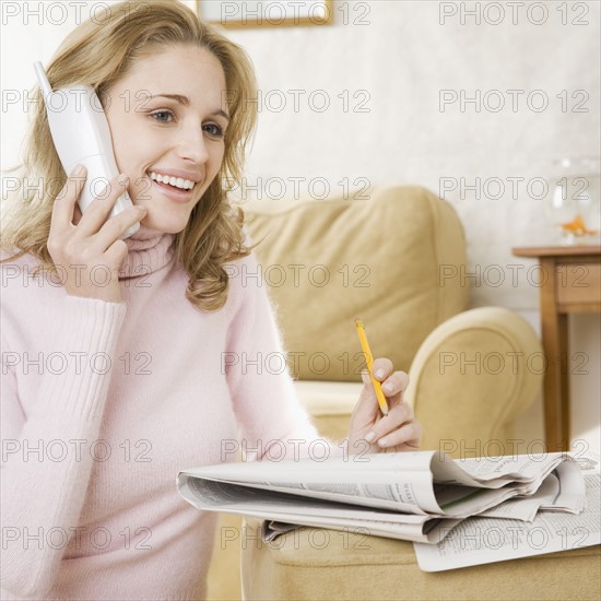 Woman on telephone with newspaper. Date : 2006