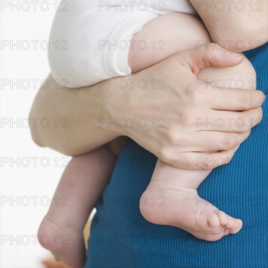 Close up of baby’s legs being held by mother. Date : 2006