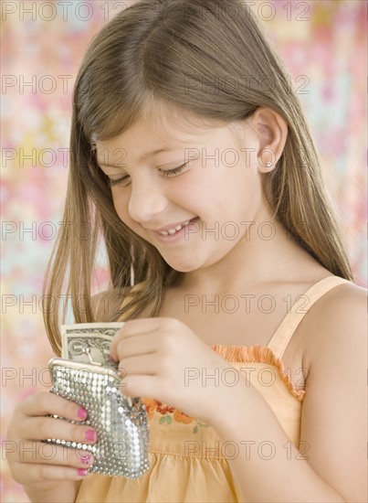 Young girl putting money in change purse. Date : 2006