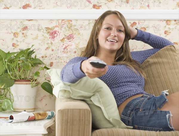 Young woman sitting on sofa with remote control. Date : 2006