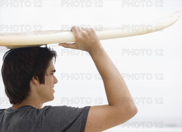 Man carrying surfboard on head . Date : 2006