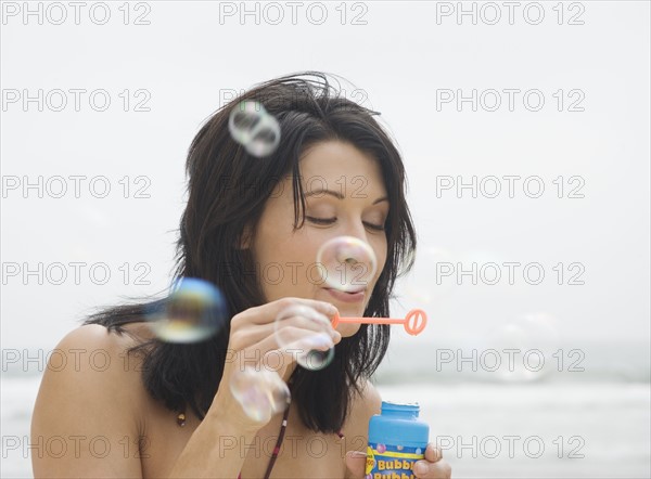 Woman blowing bubbles at beach. Date : 2006