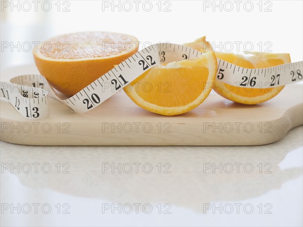 Orange halves and tape measure on cutting board. Date : 2006