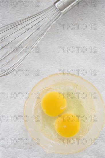 High angle view of whisk next to eggs in bowl. Date : 2006