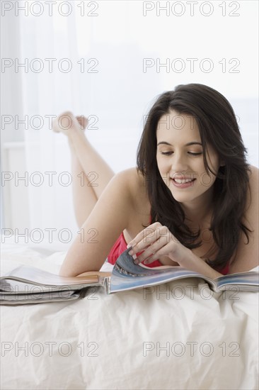 Woman reading magazines in bed. Date : 2007
