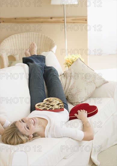 Woman laying on sofa with box of candy. Date : 2007