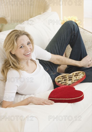 Woman laying on sofa with box of candy. Date : 2007