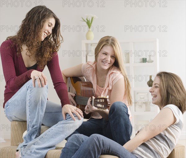 Teenage girls laughing and playing guitar. Date : 2007