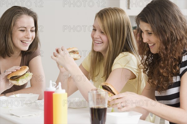 Teenage girls eating hamburgers. Date : 2007