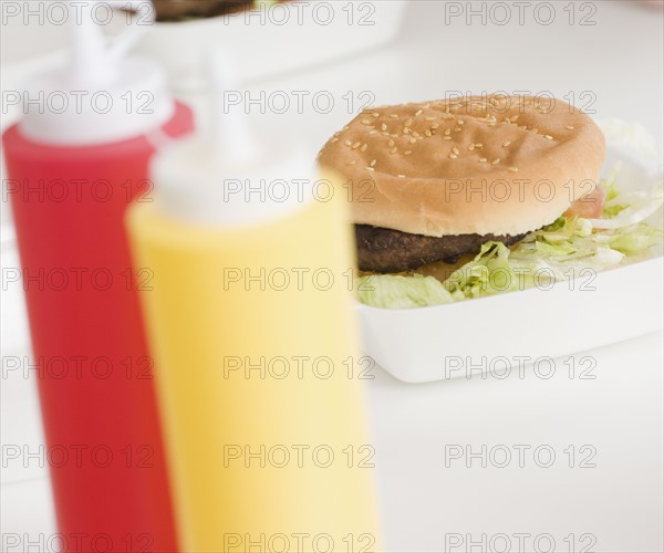 Close up of hamburger and condiment bottles. Date : 2007