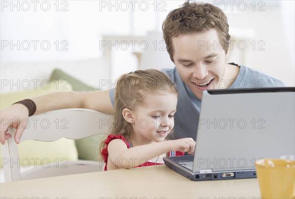 Father and daughter typing on laptop. Date : 2007