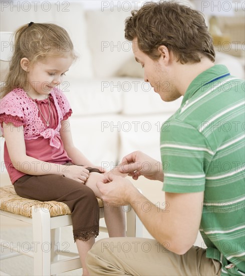 Father putting bandage on daughter. Date : 2007