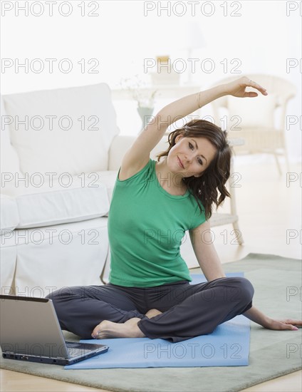 Woman practicing yoga next to laptop. Date : 2007