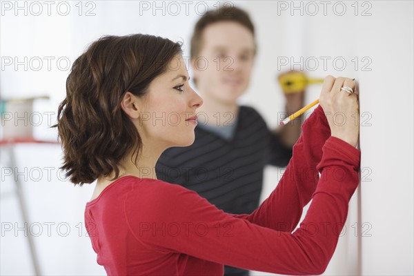 Couple using measuring tape on wall. Date : 2007