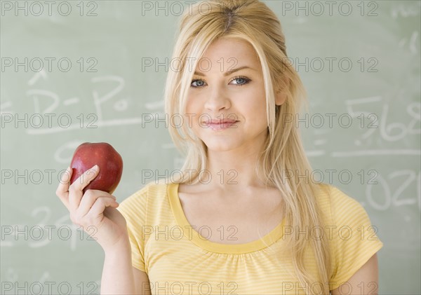 Woman holding apple in front of blackboard. Date : 2007