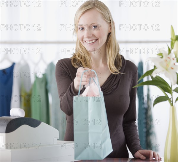 Clothing store sales clerk handing package over counter. Date : 2007