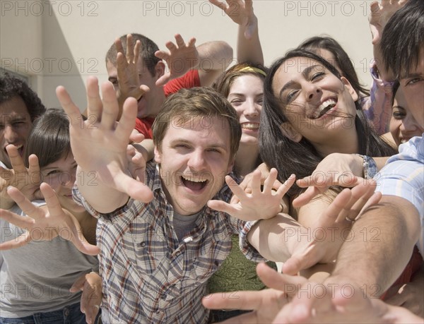 Friends reaching out hands and laughing. Date : 2007