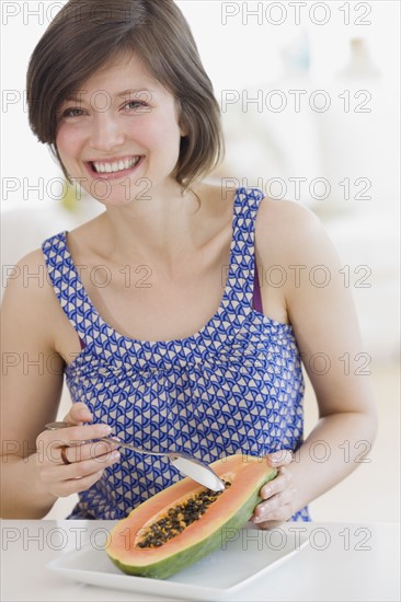 Woman eating fruit in kitchen. Date : 2007