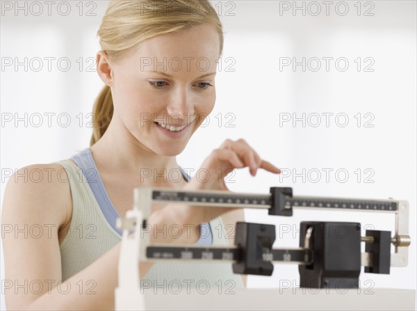 Woman weighing self on scale. Date : 2007