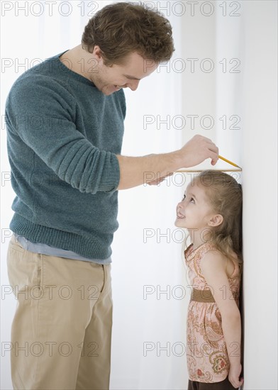Father measuring daughter’s height on wall. Date : 2007