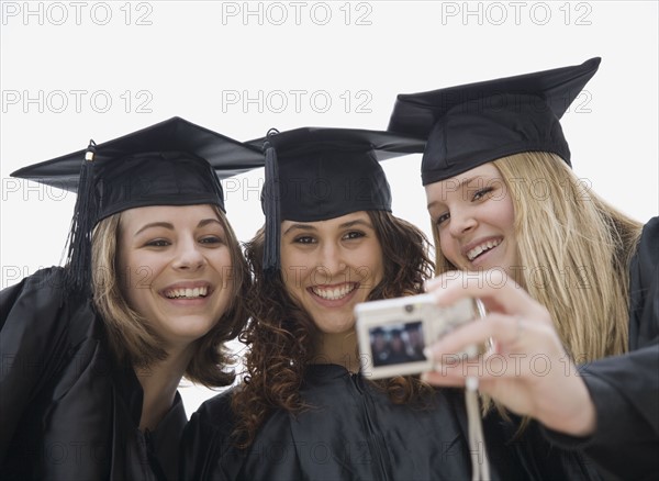 Teenage girls taking own photograph on graduation day. Date : 2007