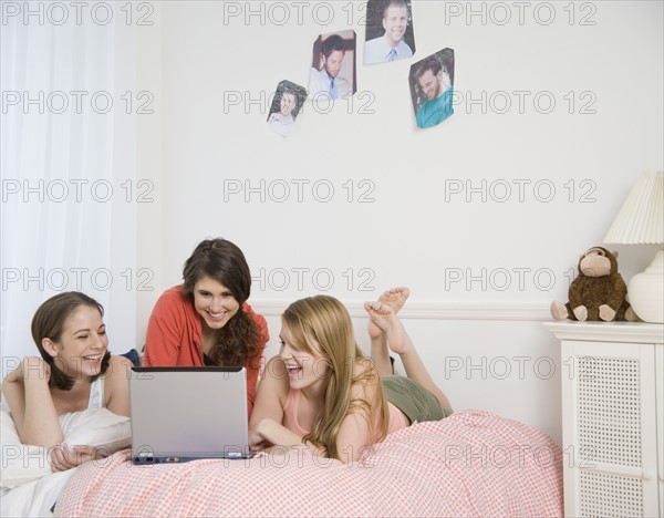 Teenage girls looking at laptop on bed. Date : 2007