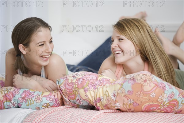 Teenage girls laughing on bed. Date : 2007