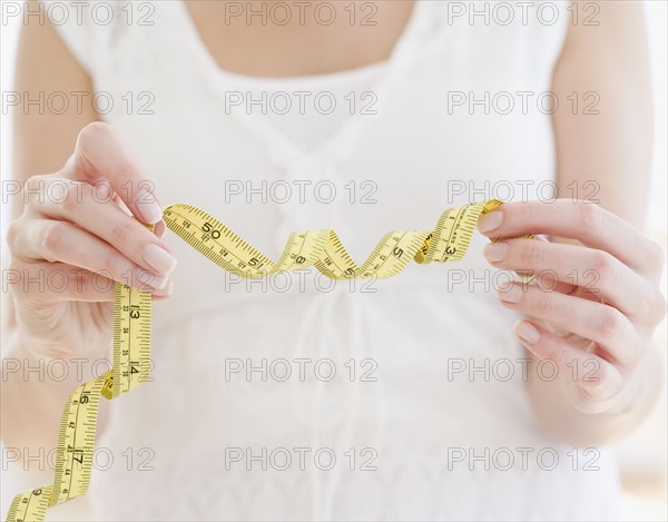 Woman holding curled tape measure. Date : 2007