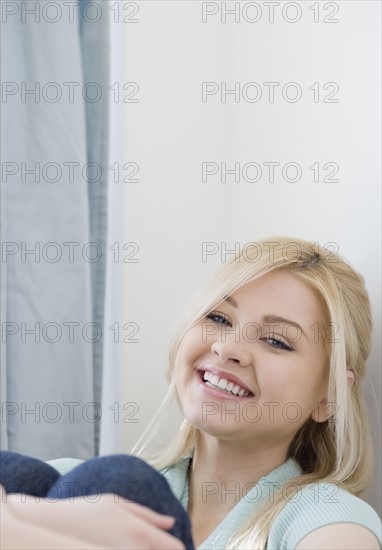 Woman smiling and hugging knees. Date : 2007