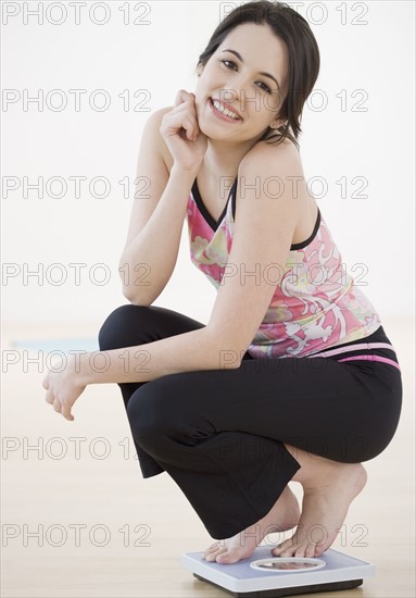 Portrait of woman crouching on bathroom scale. Date : 2007