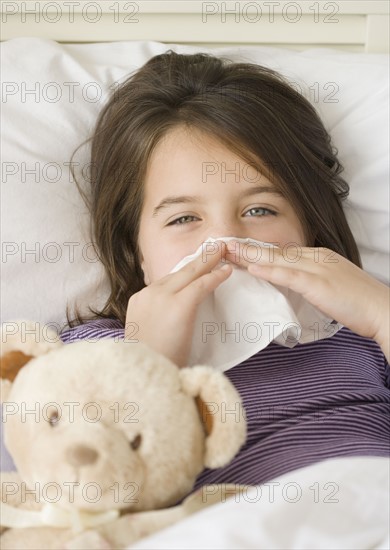 Close up of girl blowing nose in bed. Date : 2006