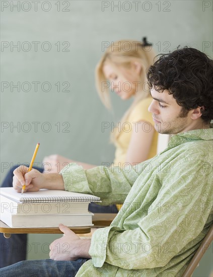 Man writing at desk in classroom. Date : 2007
