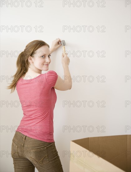 Woman hammering nail in wall. Date : 2006