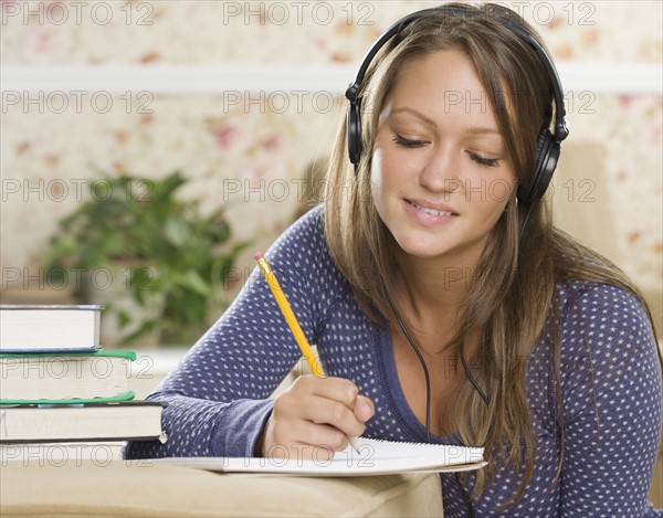 Young woman wearing headphones and doing homework. Date : 2006