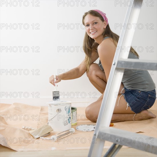 Young woman on tarp with paintbrush and paint can. Date : 2006