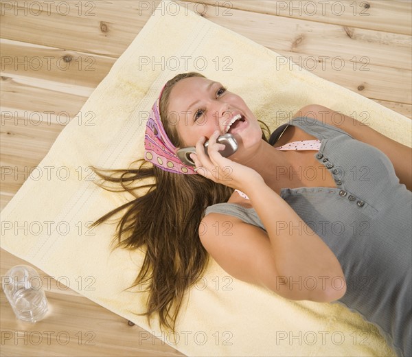 Young woman laying on floor using cell phone. Date : 2006