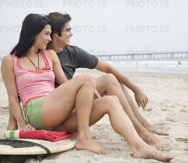 Couple sitting on surfboard at beach. Date : 2006