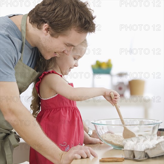 Father and daughter mixing batter in kitchen. Date : 2007