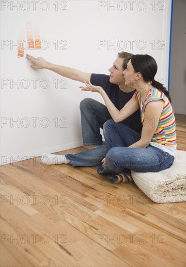 Couple looking at paint swatches on wall. Date : 2006