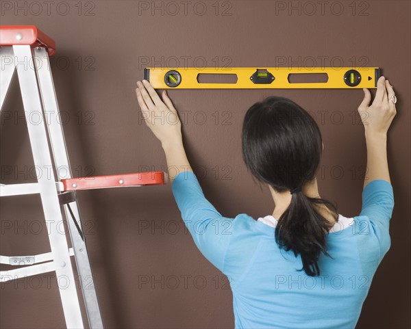 Woman using level on wall. Date : 2006